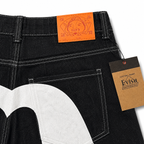 EVISU Denim Shorts featuring a Distressed, Paneled "Big M" Print